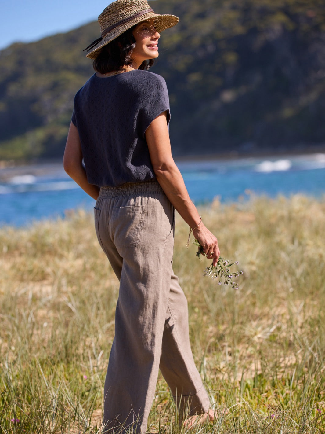 Woman walking on a grassy hill with ocean view
