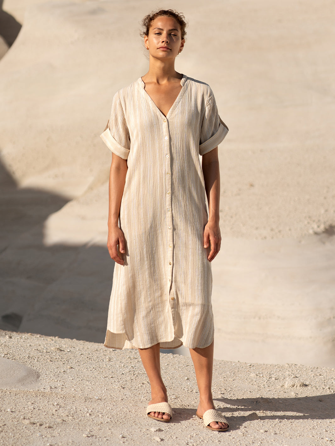 Woman wearing a beige dress standing against a neutral background