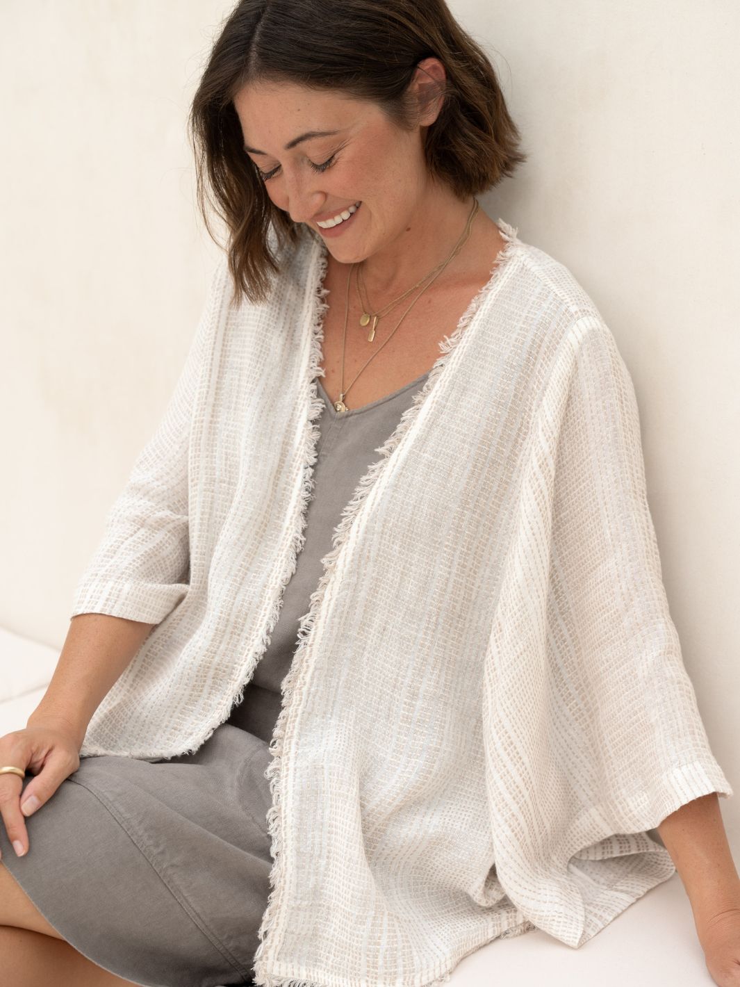 Woman wearing a white textured kimono-style garment against a plain background