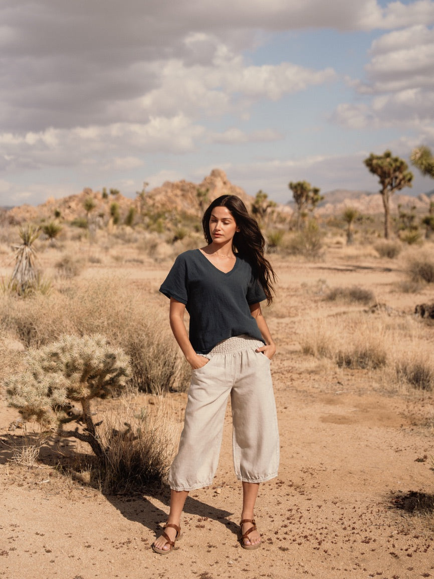 Woman standing in a desert landscape with cacti and Joshua trees.