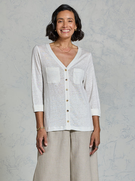 Woman wearing a white button-up shirt and beige pants against a gray background