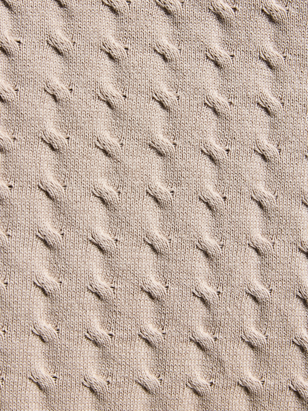 Close-up of textured beige fabric with a cable knit pattern