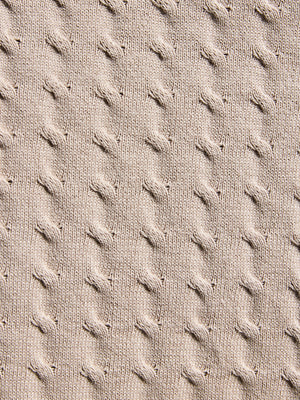 Close-up of textured beige fabric with a cable knit pattern