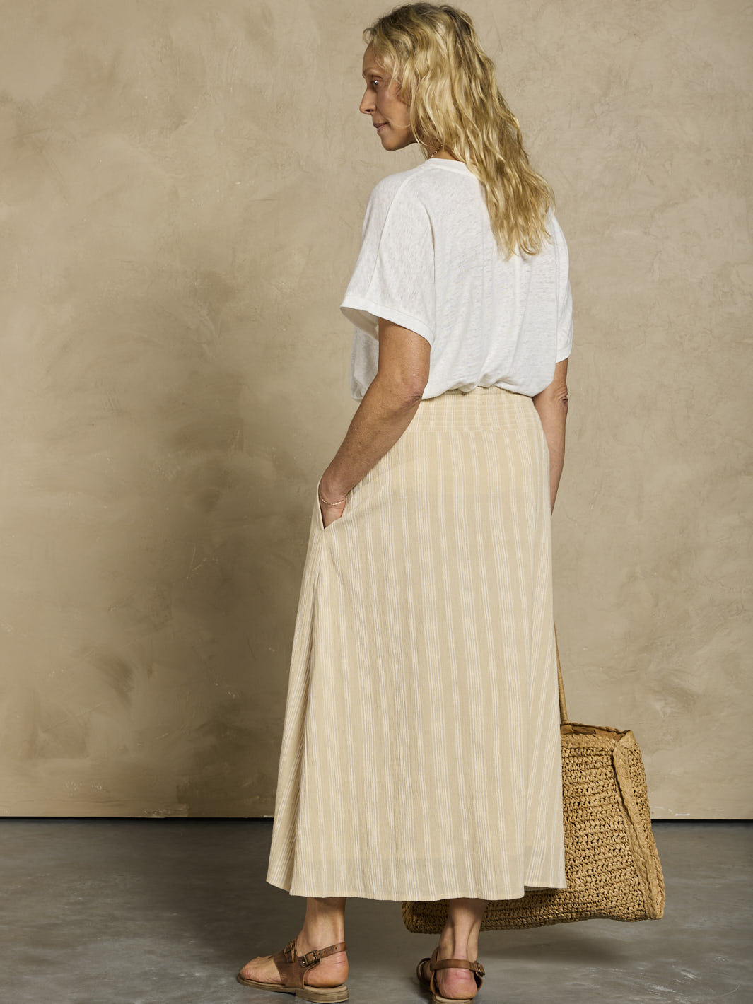 Woman wearing a white linen top and beige cotton skirt