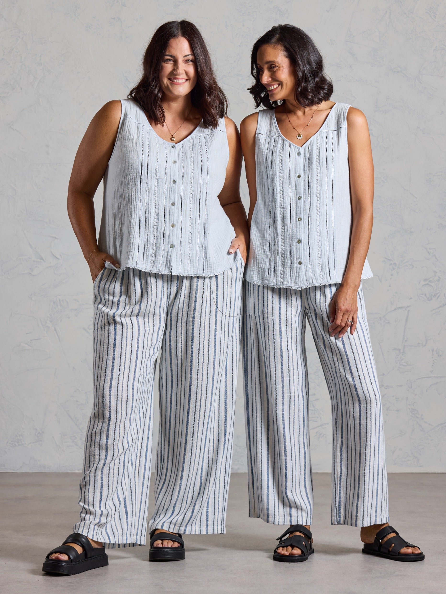 Two models wearing the Ceres Organic Cotton Top in serene blue with blue striped wide leg linen pants