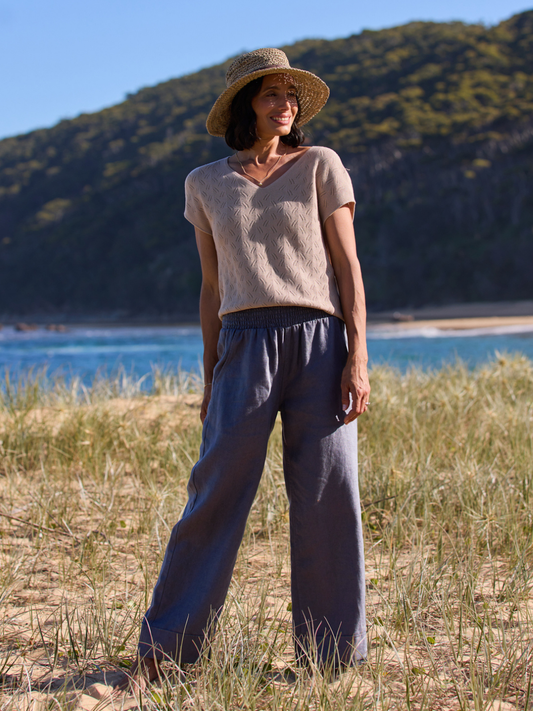 Woman standing in a natural setting with mountains and water in the background