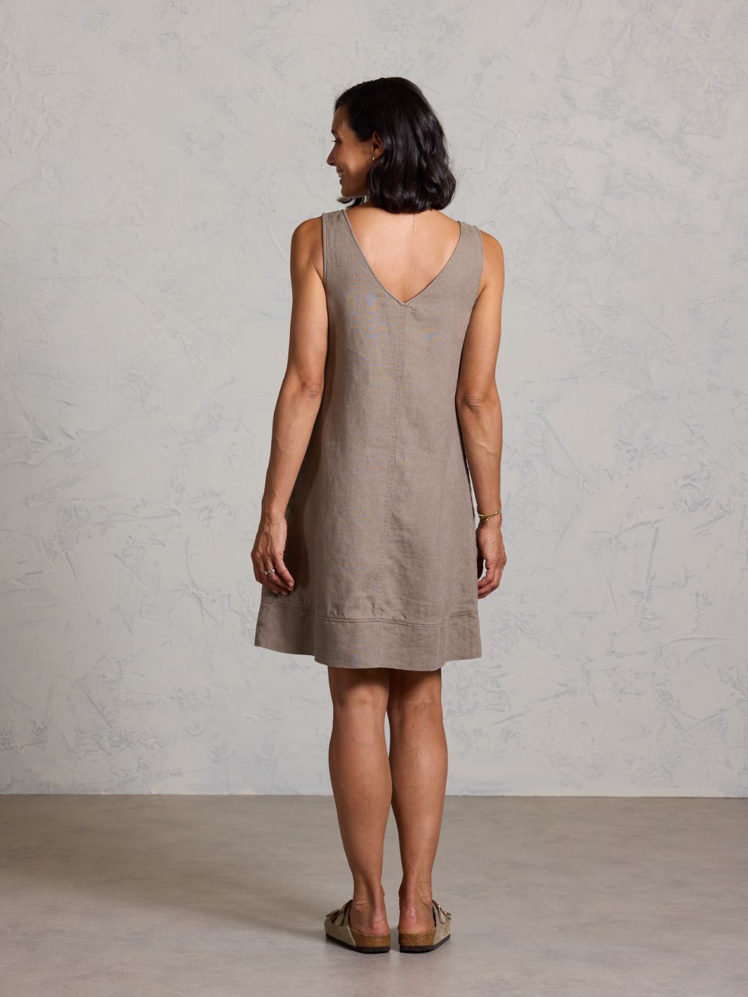 Woman wearing a beige dress against a plain background
