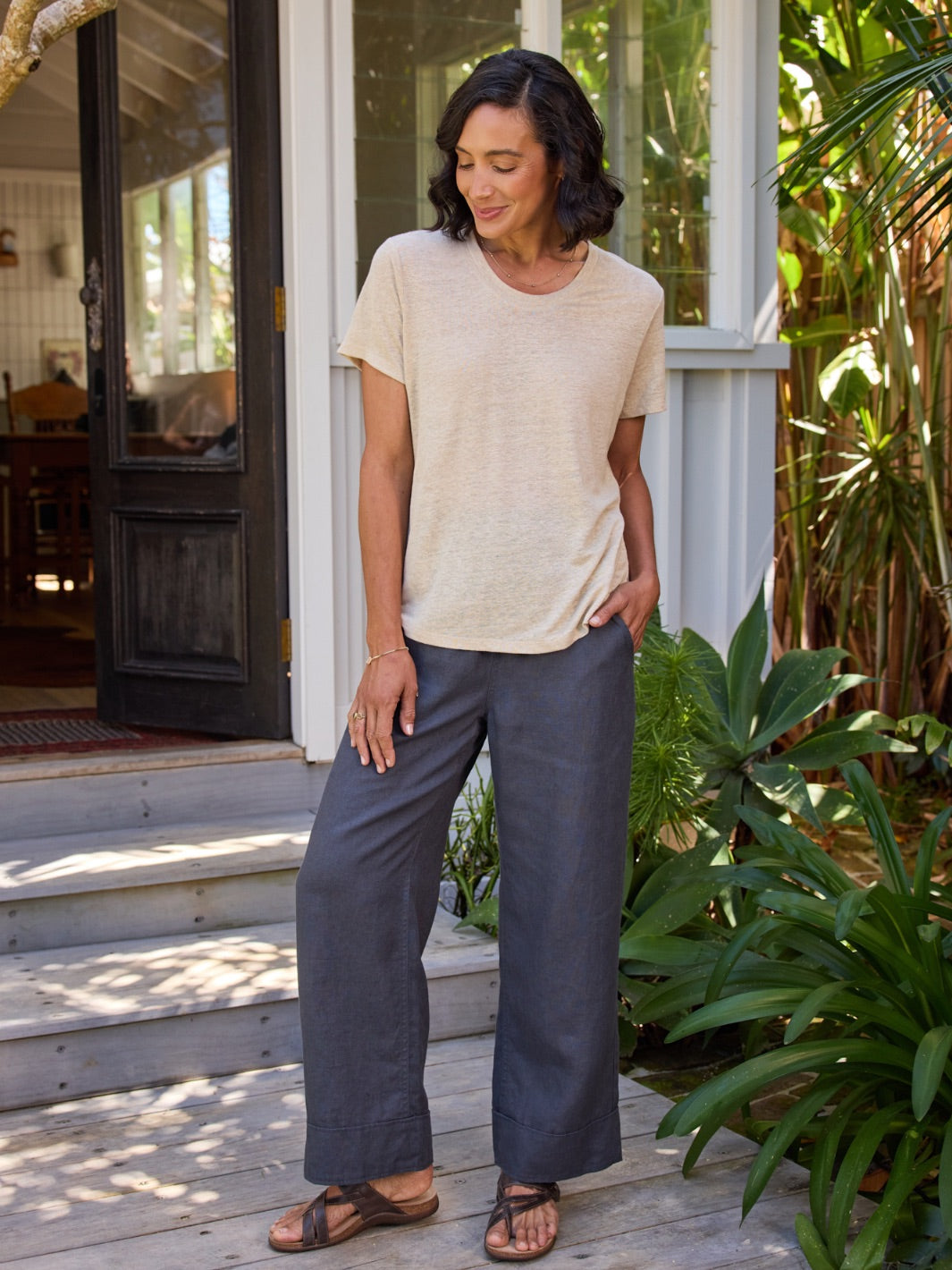 Woman standing on a wooden deck with plants and a house in the background
