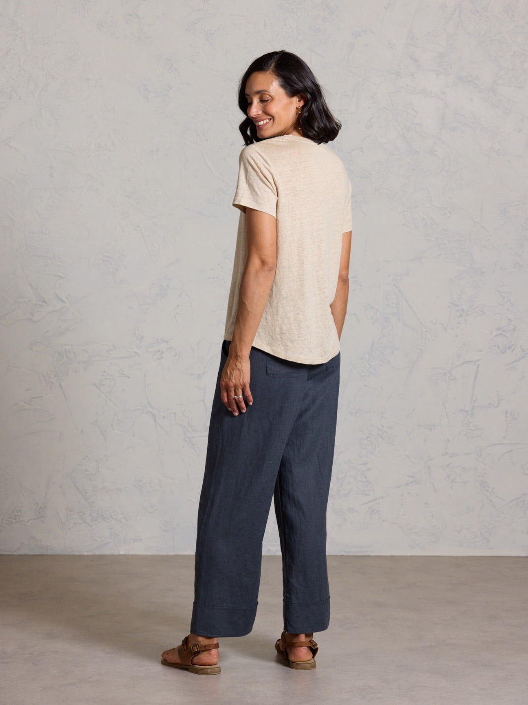 Woman wearing a beige shirt and black against a plain background