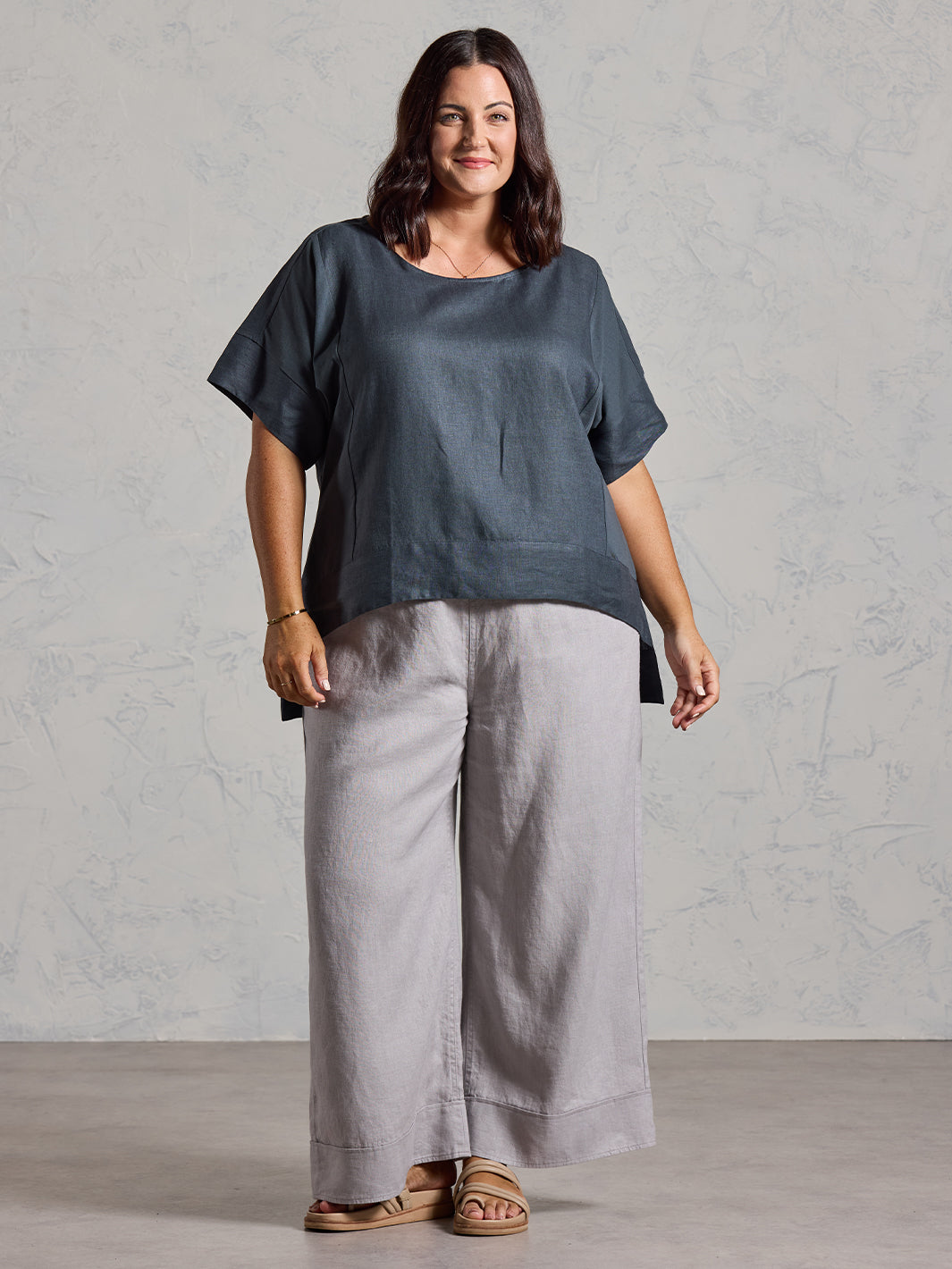 Image features woman wearing a dark top and light pants.