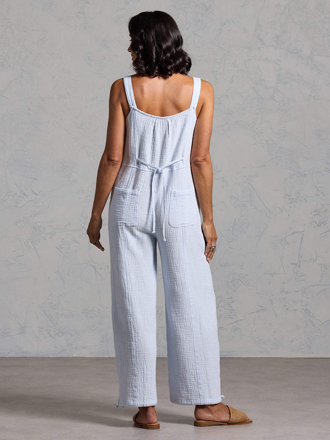 A woman wearing a serene blue cotton jumpsuit from Nomad the Label