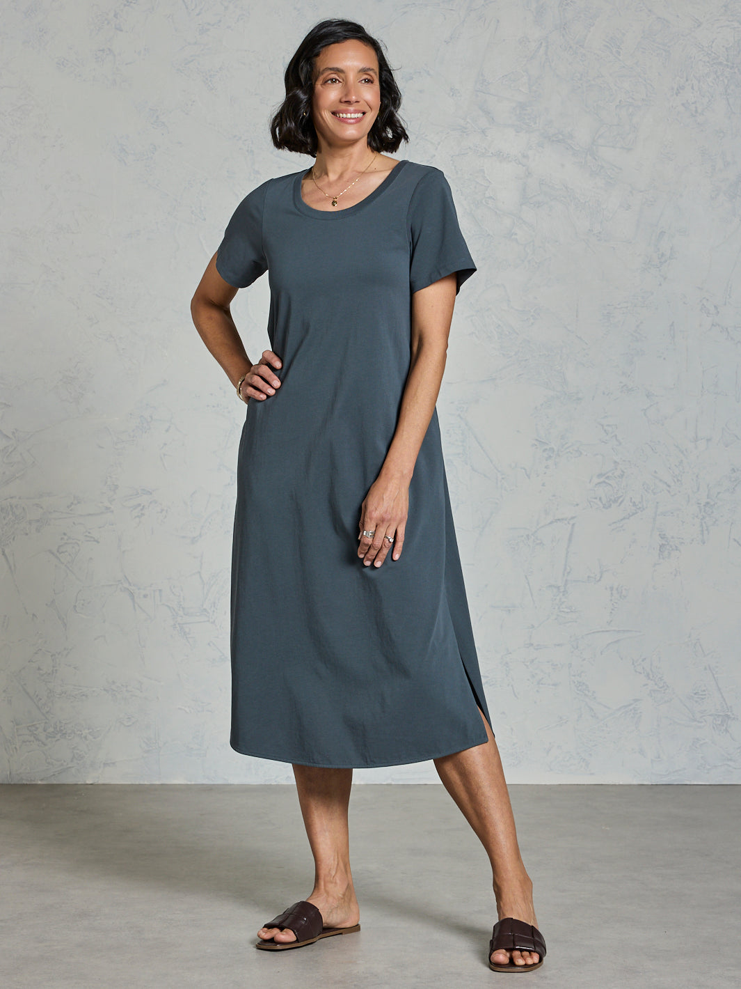 Woman wearing a gray dress standing against a plain background