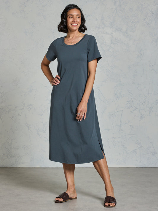 Woman wearing a gray dress standing against a plain background