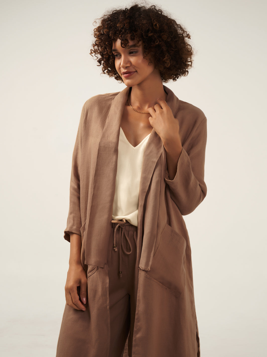 Model is wearing Nova Longline Linen Coat in Desert Sand