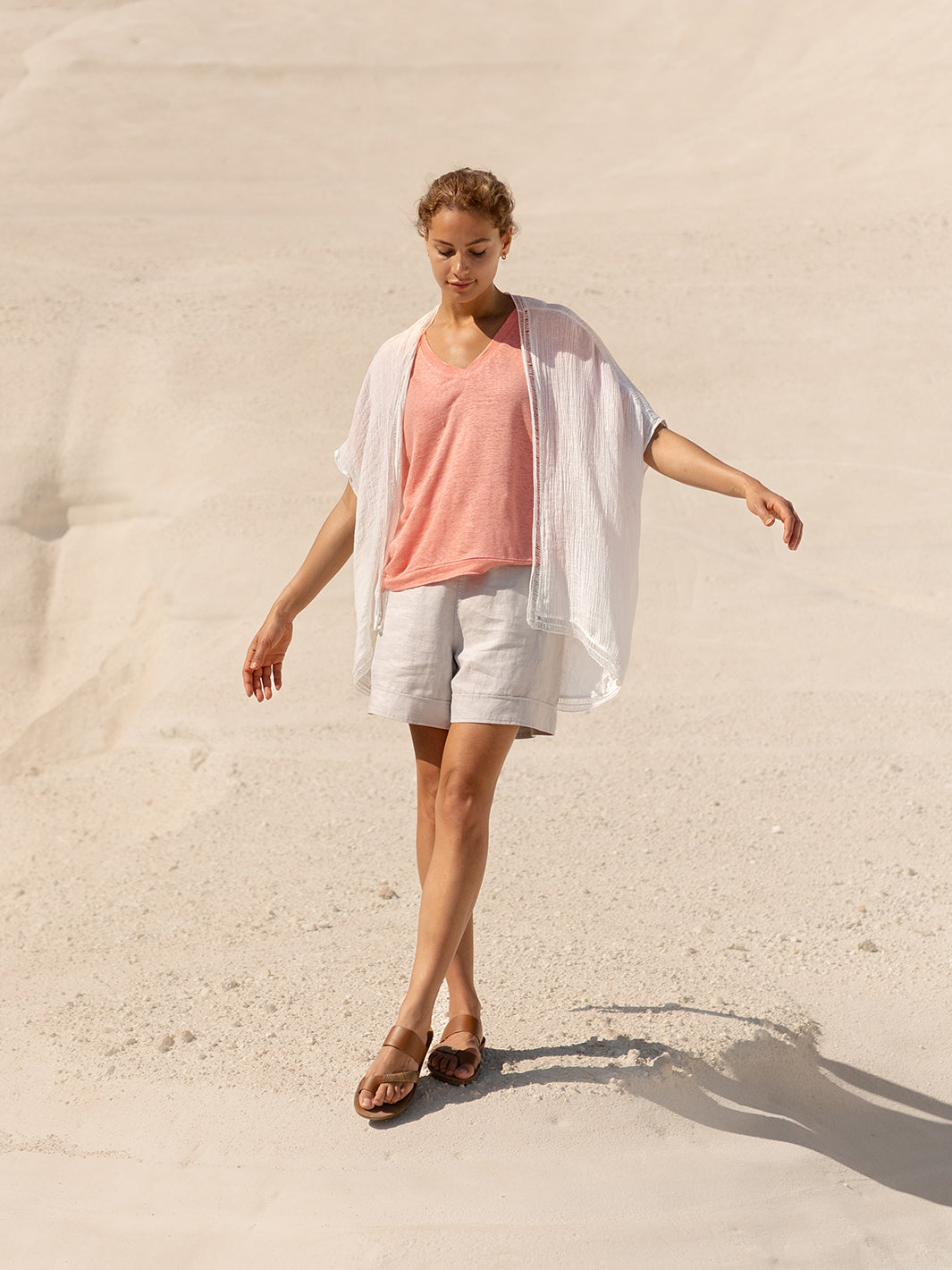 Woman in light clothing standing on sand