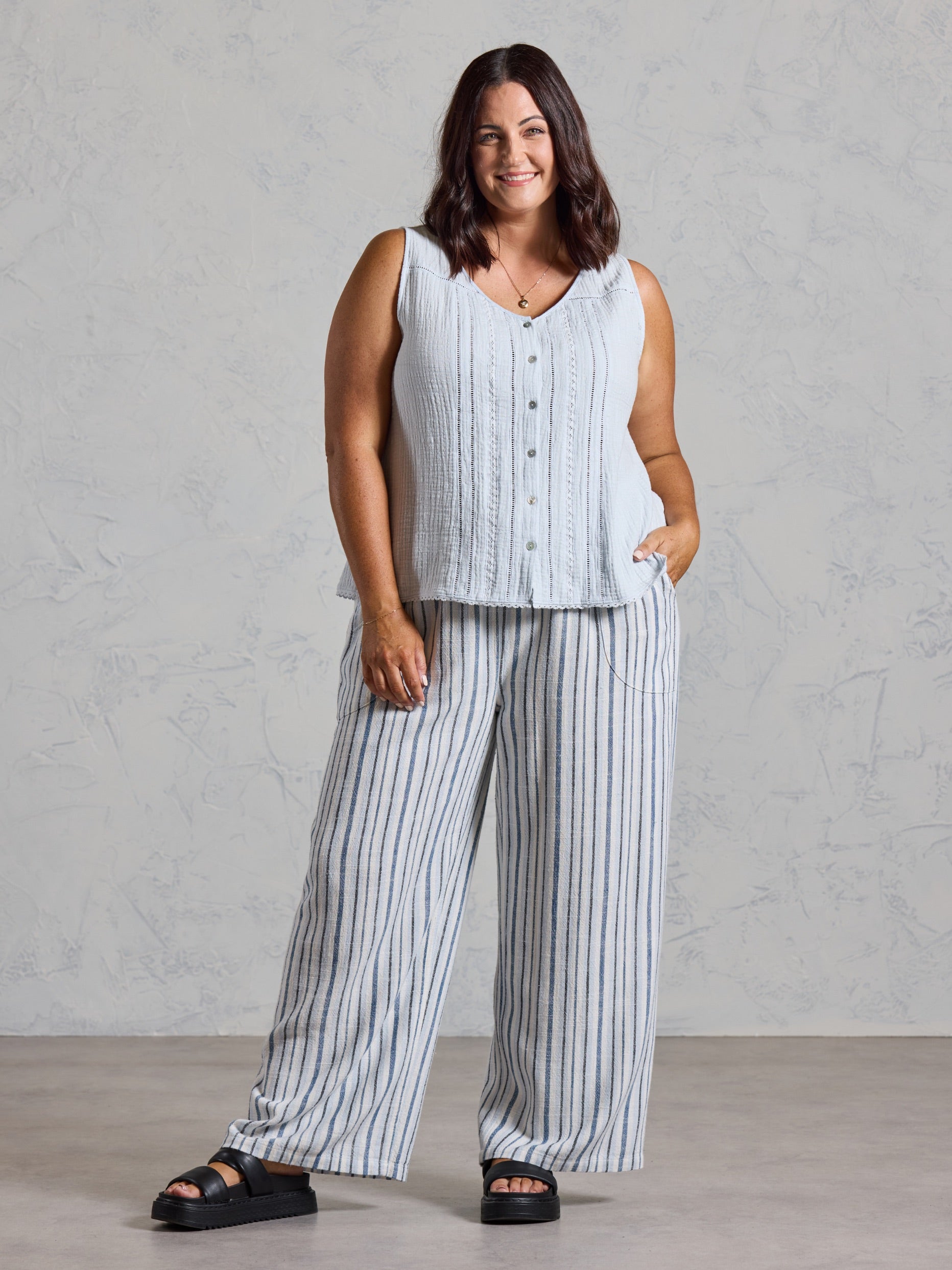 Curve model in the Ceres Organic Cotton Top in serene blue, styled with wide leg blue striped linen pants.