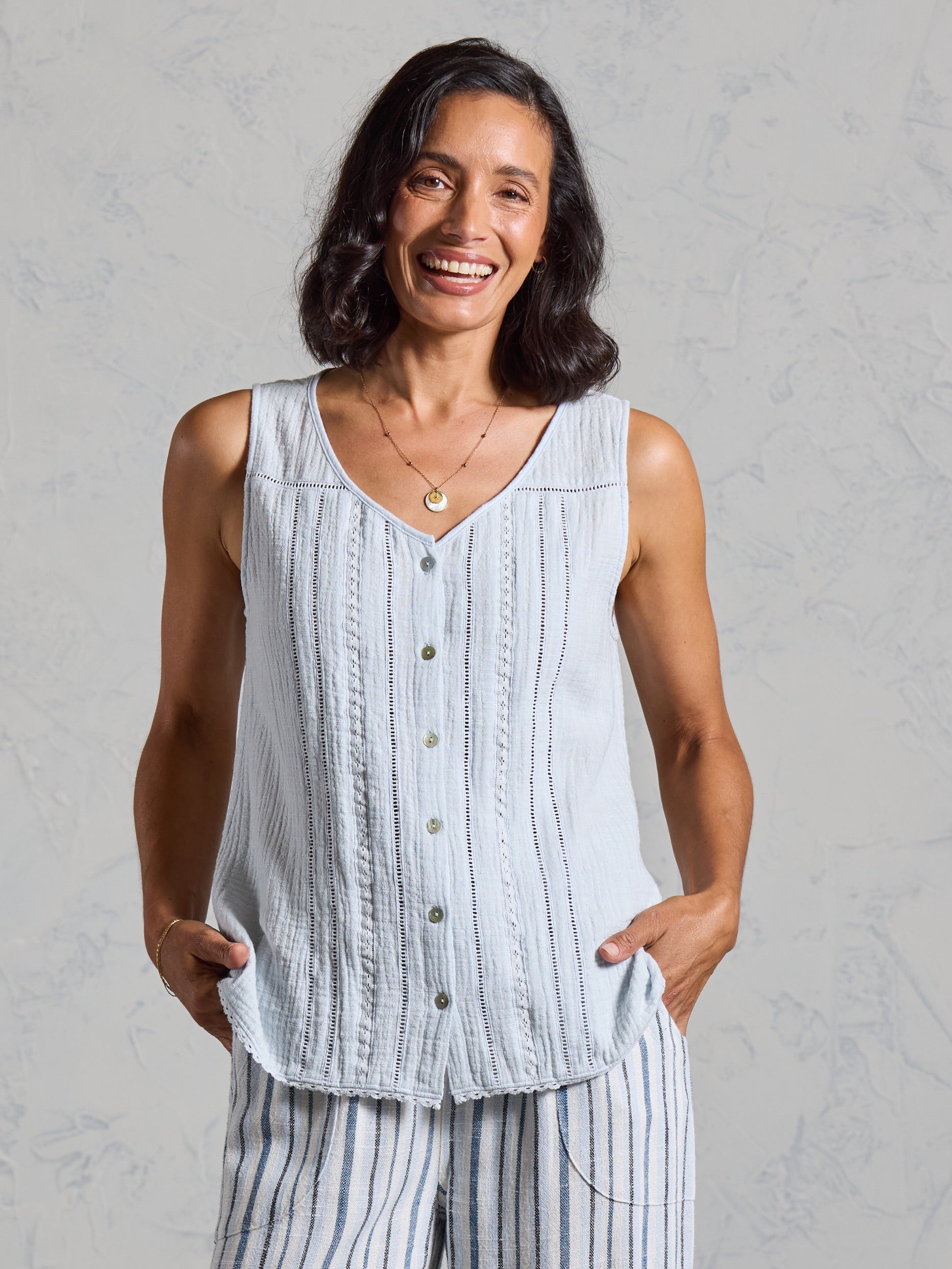 Front view of the Ceres Organic Cotton Top in serene blue, worn with blue striped linen pants.