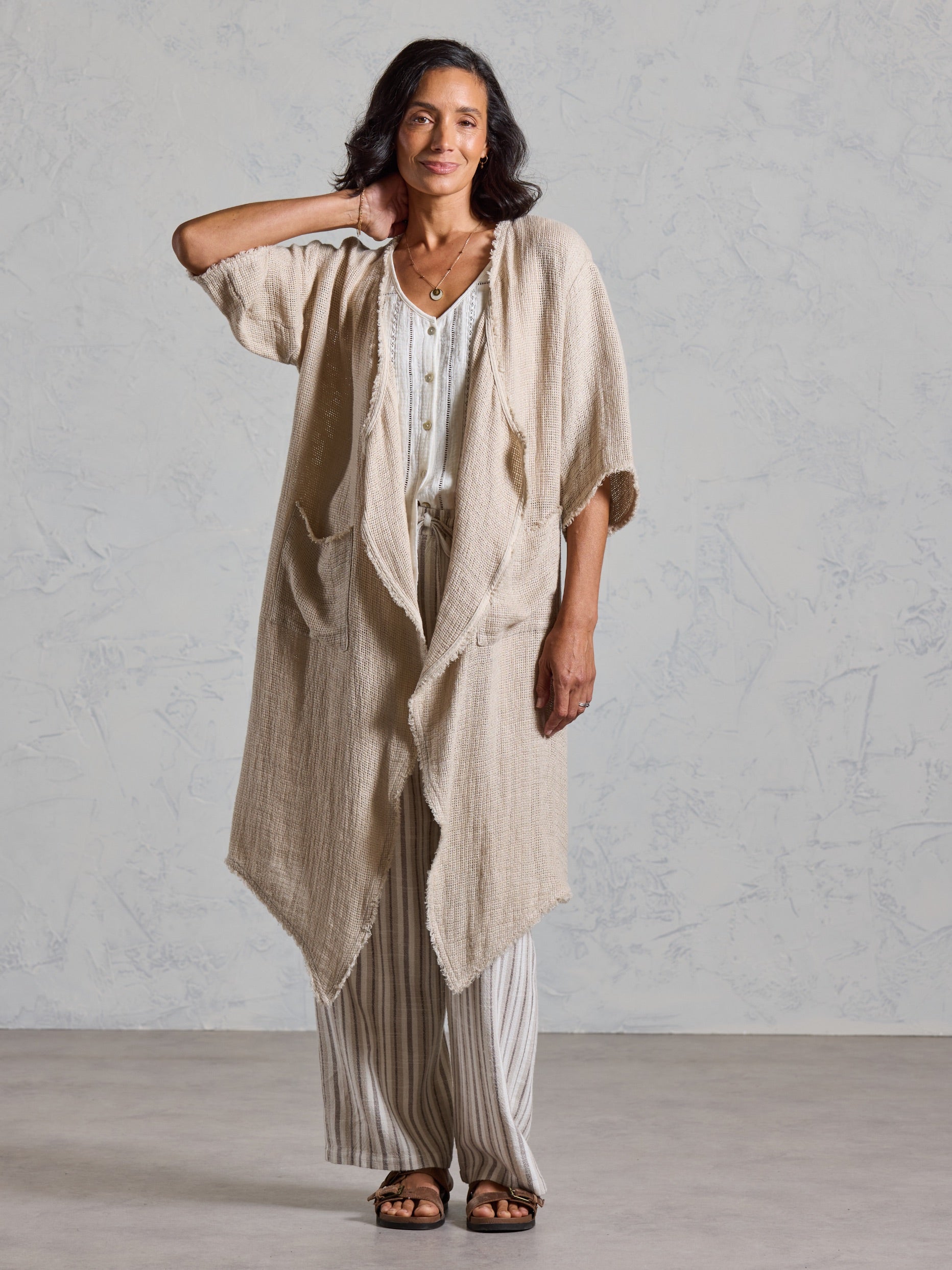 Full length view of the Laguna French Linen Kimono in natural, layered over a white top and striped linen pants.